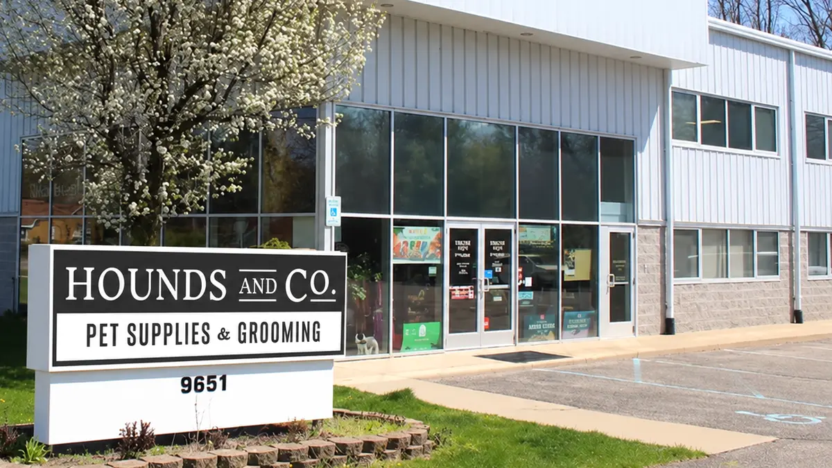 The Hounds and Co. storefront at 9651 Portage Road with its monument sign and a flowering tree